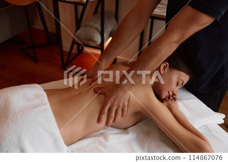 Cropped closeup shot of male massage therapist massaging female back 114867076