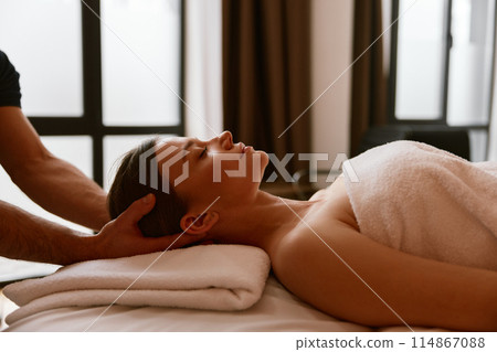 Closeup woman client relaxing under male hands doing head massage Closeup woman client relaxing under male hands doing head massage 114867088