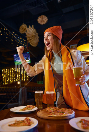 Shouting woman football fan watching TV match in sports bar Shouting woman football fan watching TV match in sports bar 114867204