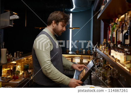 Bartender using digital panel to for processing bar visitors orders Bartender using digital panel to for processing bar visitors orders 114867261