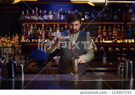 Bartender male pouting liquor to make cocktail Bartender male pouting liquor to make cocktail 114867291