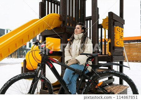 Woman Sitting on Bench Next to Bike 114867851