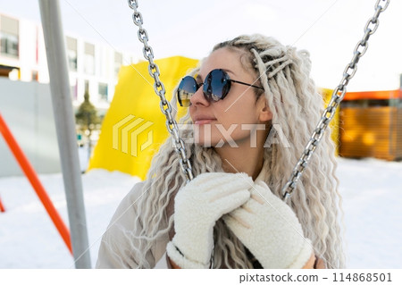 Woman Sitting on Swing in Snow 114868501