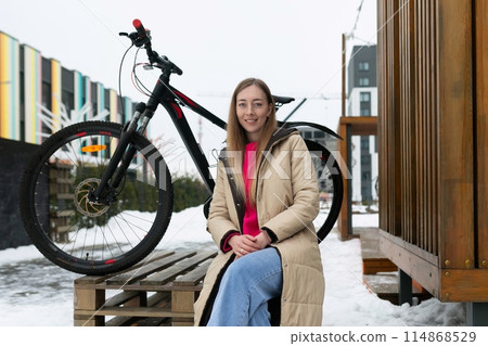 Woman Sitting on Bench Next to Bike 114868529