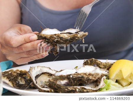 Woman eat with a fork oysters. Lifestyle concept Woman eat with a fork oysters. Lifestyle concept 114869203