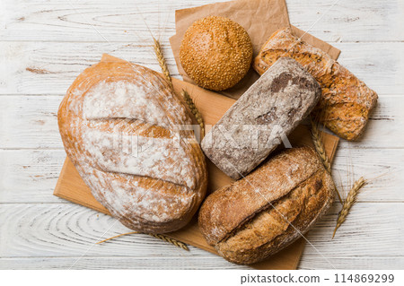 Assortment of freshly baked bread with napkin on rustic table top view. Healthy unleavened bread. French bread Assortment of freshly baked bread with napkin on rustic table top view. Healthy unleavened bread. French bread 114869299