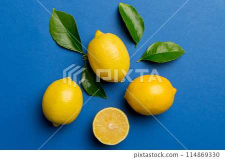 Many fresh ripe lemons with green leaves on colored background, top view, space for text 114869330