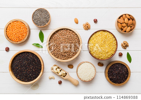 Various superfoods in smal bowl on colored background. Superfood as rice, chia, quinoa, lentils, nuts, sesame seeds, almonds. top view copy space Various superfoods in smal bowl on colored background. Superfood as rice, chia, quinoa, lentils, nuts, sesame seeds, almonds. top view copy space 114869388