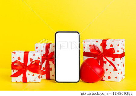 mobile phone with blank screen on colored background with hearts, calendar and gift box, valentine day concept perspertive view flat lay 114869392