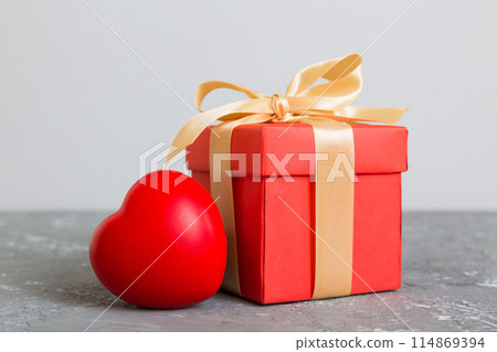 gift box with red bow and red heart on colored background. Perspective view. Flat lay gift box with red bow and red heart on colored background. Perspective view. Flat lay 114869394