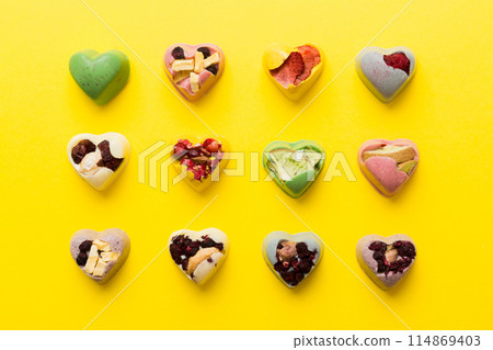 chocolate sweets in the form of a heart with fruits and nuts on a colored background. top view with space for text, holiday concept 114869403