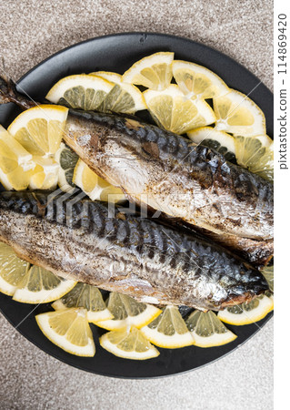 Oven-baked mackerel sea fish dish served with fresh lemon slices Oven-baked mackerel sea fish dish served with fresh lemon slices 114869420
