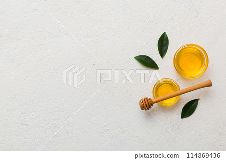 Honey jar with wooden honey dipper on white background top view with copy space. Delicious honey bottle Honey jar with wooden honey dipper on white background top view with copy space. Delicious honey bottle 114869436