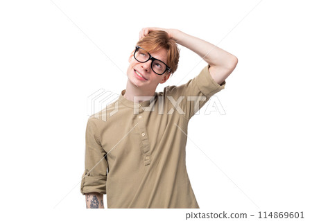 young positive red-haired european man dressed in a light brown shirt with a tattoo on his arm 114869601