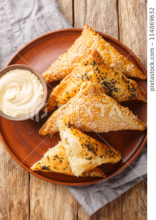 Homemade freshly baked Chicken Puffs with Cheese and Herbs served with Dipping Sauce close up in a plate on a wooden table. Vertical top view 114869632
