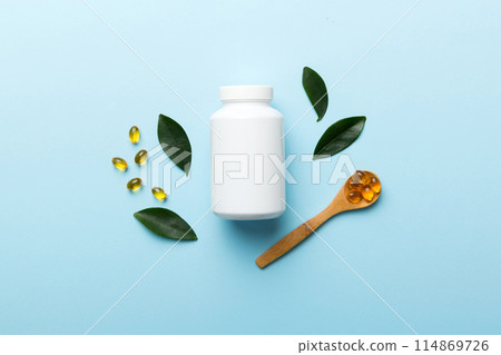 Omega-3 capsules lie in white bottle on a table with green leaves background. Fish oil tablets. Biologically active additives. omega 6, omega 9, vitamin A, E, D, vitamin D3 top view with copy space 114869726