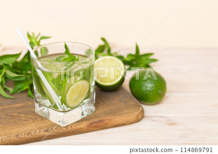 Mojito cocktail. Refreshing mojito cocktail with lime, lemon and mint in a tall glass with a stick Mojito cocktail. Refreshing mojito cocktail with lime, lemon and mint in a tall glass with a stick 114869791