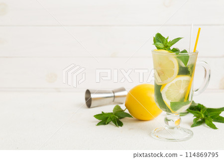 Mojito cocktail. Refreshing mojito cocktail with lime, lemon and mint in a tall glass with a stick Mojito cocktail. Refreshing mojito cocktail with lime, lemon and mint in a tall glass with a stick 114869795