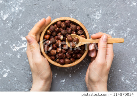 Woman hands holding a wooden bowl with hazelnut nuts. Healthy food and snack. Vegetarian snacks of different nuts Woman hands holding a wooden bowl with hazelnut nuts. Healthy food and snack. Vegetarian snacks of different nuts 114870034