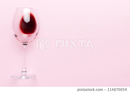 One glasses of red wine at wine tasting. Concept of red wine on colored background. Top view, flat lay design One glasses of red wine at wine tasting. Concept of red wine on colored background. Top view, flat lay design 114870059