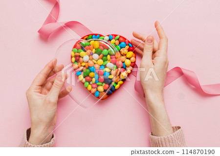 Female hands with delicious candies in box on color background 114870190