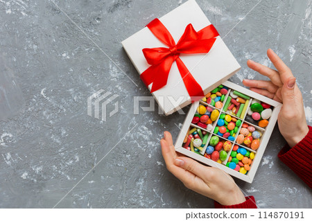 Female hands with delicious candies in box on color background 114870191