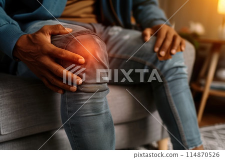 Man sitting on a couch and holding his knee. he having knee pain. Generative AI 114870526