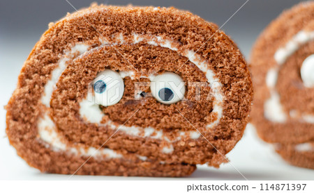 Chocolate sponge roll with a vanilla flavour filling with decorating sweet eyes, chocolate swiss roll 114871397