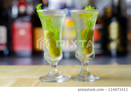 Shaken vodka and pickle juice with ice in a shot glass and garnished with small pickled cucumber and dill Shaken vodka and pickle juice with ice in a shot glass and garnished with small pickled cucumber and dill 114871411