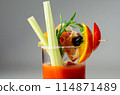 A glass of Bloody Mary drink with a celery spear and an orange slice on top 114871489