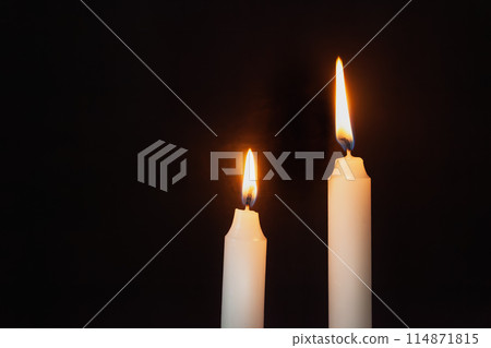 Two lit candles on a dark background 114871815