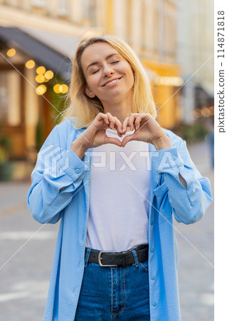 Woman makes symbol of love showing heart sign to camera charity gratitude donation positive feelings 114871818