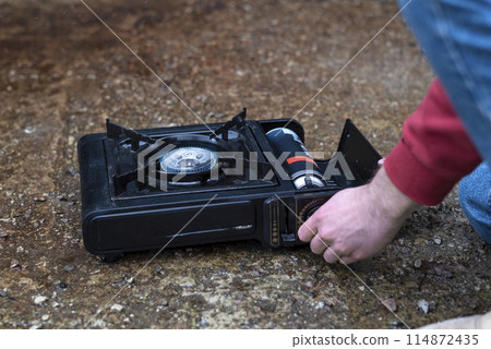 Active lifestyle. A man's hand turns on a portable gas stove. An alternative source for cooking at home during a power outage. 114872435