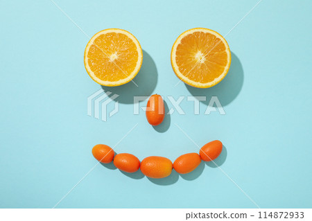 Whole kumquats and two half of orange on blue background, top view Whole kumquats and two half of orange on blue background, top view 114872933