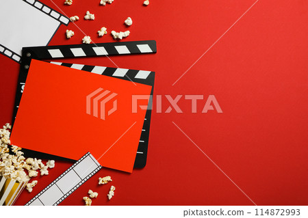 Clapperboard, paper cup with popcorn, film and reel on red background, space for text Clapperboard, paper cup with popcorn, film and reel on red background, space for text 114872993