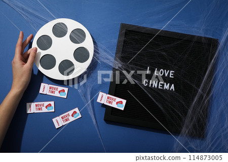 Letter board with text, reel, tickets, hand and spider web on blue background, top view Letter board with text, reel, tickets, hand and spider web on blue background, top view 114873005