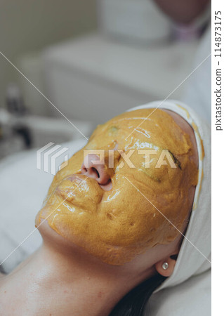 A girl at a cosmetologist does cosmetic procedures. Alginate mask 114873175