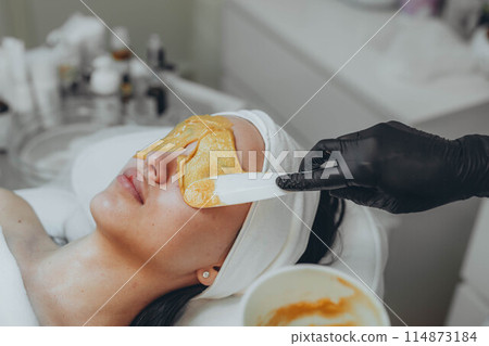 A girl at a cosmetologist does cosmetic procedures. Alginate mask 114873184