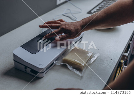 man vacuum-packing cheese with a vacuum cleaner man vacuum-packing cheese with a vacuum cleaner 114873195