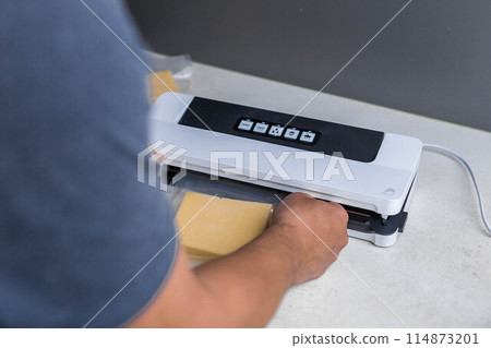 man vacuum-packing cheese with a vacuum cleaner 114873201