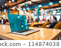 A laptop computer is placed on a wooden table inside a restaurant 114874038
