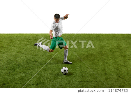 Side view photo of soccer player kicking, passing ball in motion on green grass field against a white background Side view photo of soccer player kicking, passing ball in motion on green grass field against a white background 114874783