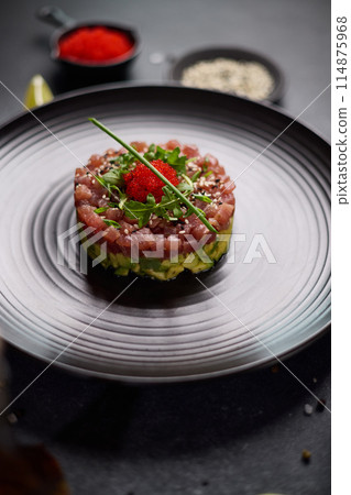 Tuna and avocado tartare on a dark ceramic plate Tuna and avocado tartare on a dark ceramic plate 114875968