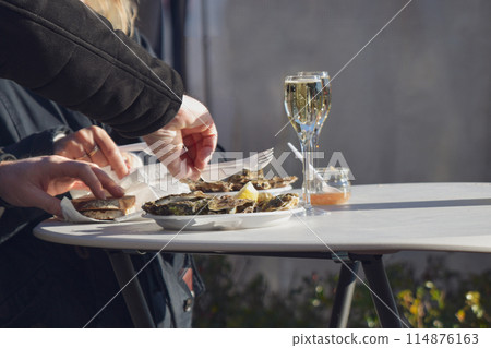 Woman eating fresh oysters at Christmas market in Paris Woman eating fresh oysters at Christmas market in Paris 114876163