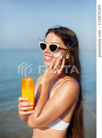 Woman smile applying sun cream on face. Skincare. Body Sun protection. sunscreen. Female smear moisturizing lotion on skin 114876305