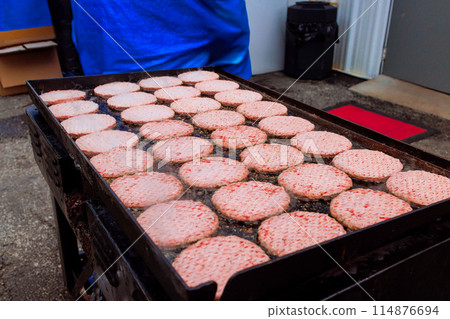 During burger cooking, chefs prepare burgers on gas grill stove in restaurant kitchen During burger cooking, chefs prepare burgers on gas grill stove in restaurant kitchen 114876694
