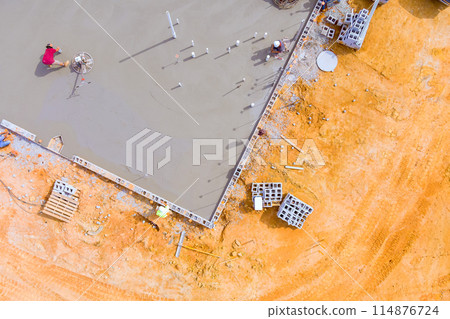 After concrete is poured on wet foundation, mason polishes concrete using concrete polishing machine. After concrete is poured on wet foundation, mason polishes concrete using concrete polishing machine. 114876724