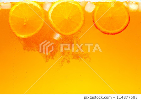 Textured photo. Orange slices with ice cubes adorns refreshing tropical drink. Abstract wallpaper. Sweet and sour. 114877595