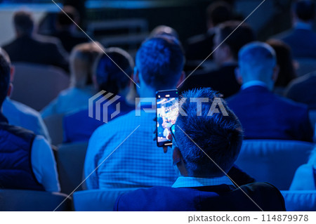 Businessman using smartphone at a conference presentation Businessman using smartphone at a conference presentation 114879978