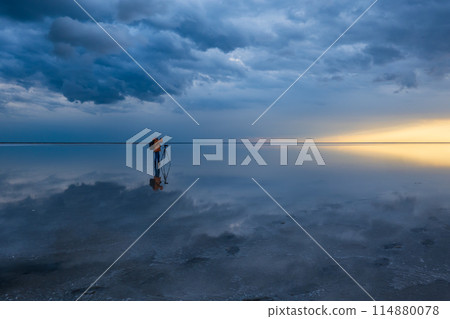 Photographer capturing dramatic skies over calm waters 114880078